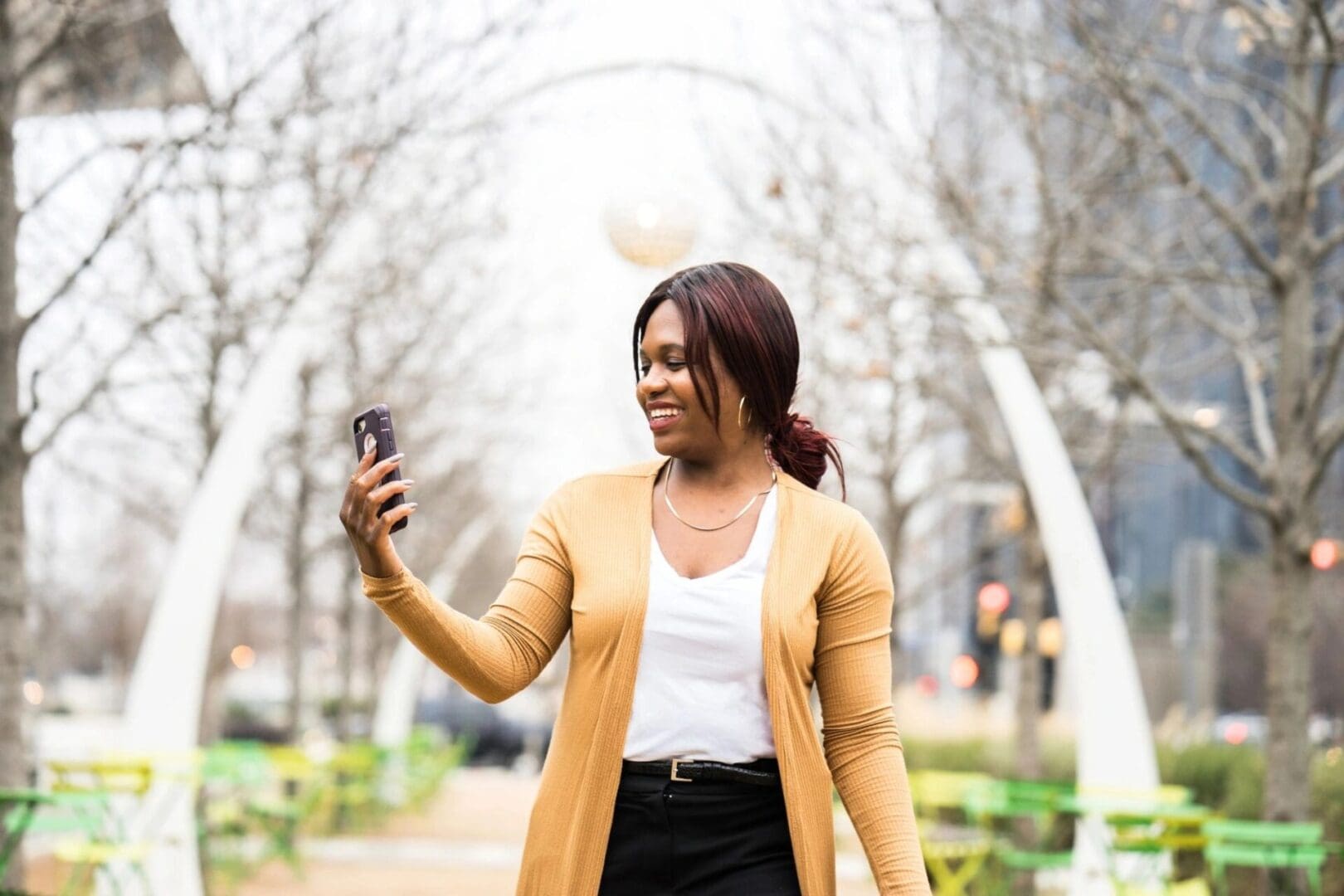 A woman in white shirt and black skirt holding up a cell phone.