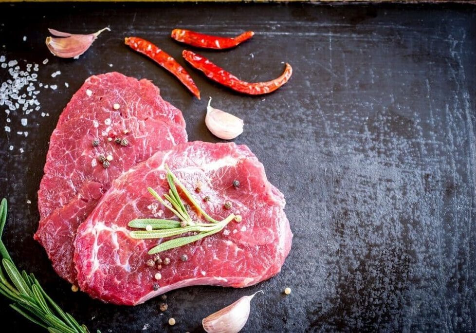 Raw beef steaks with spices and rosemary.