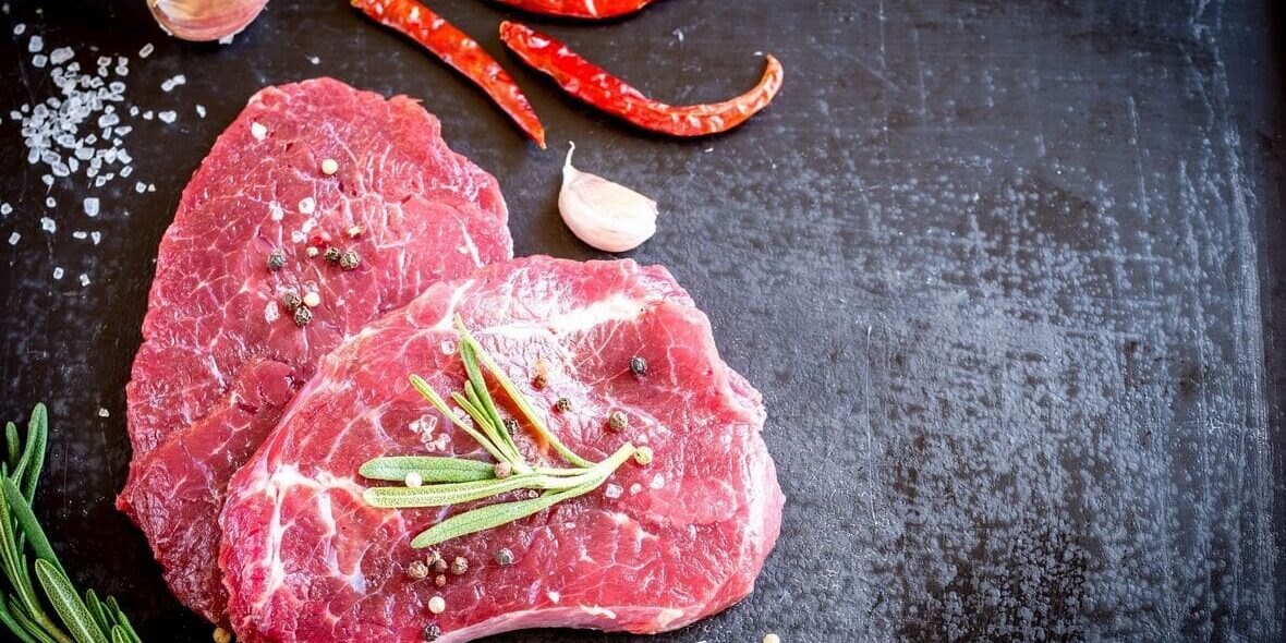 Raw beef steaks with spices and rosemary.