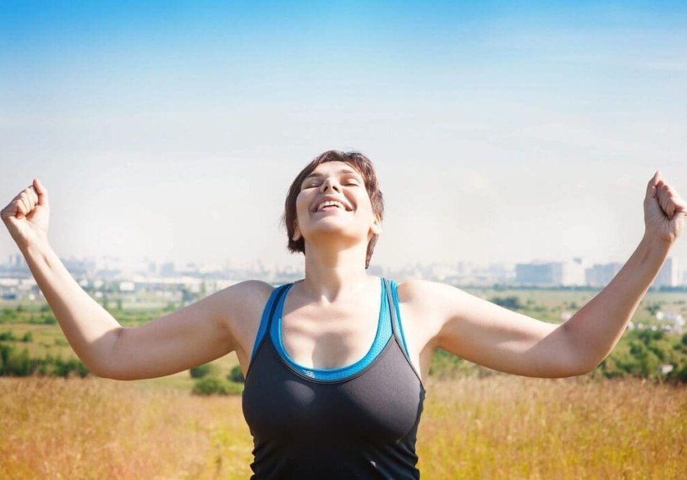 Woman in sportswear with arms raised.