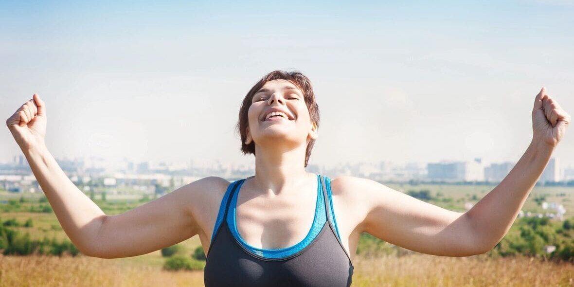 Woman in sportswear with arms raised.