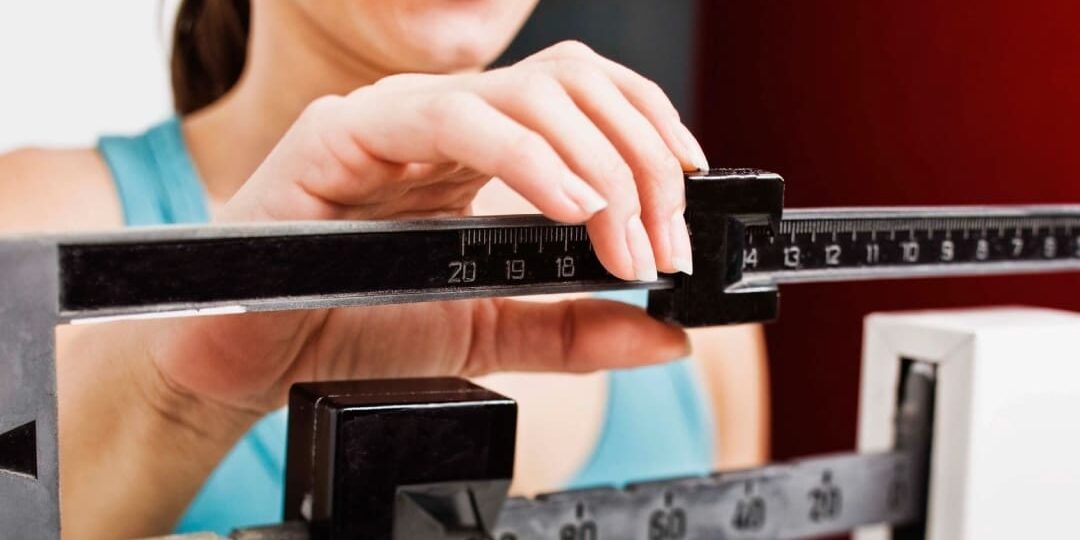 A woman is smiling while standing on a scale.